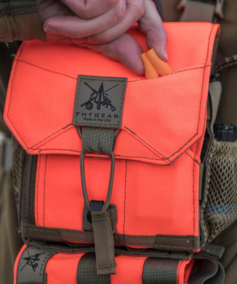 Bright orange FHFGEAR hunting pouch with earplugs in top pocket and logo.