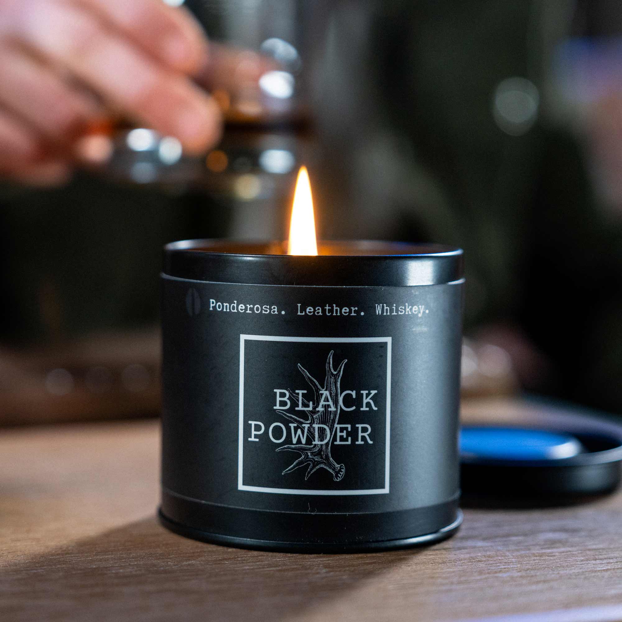 Lit Black Powder candle on wood table.