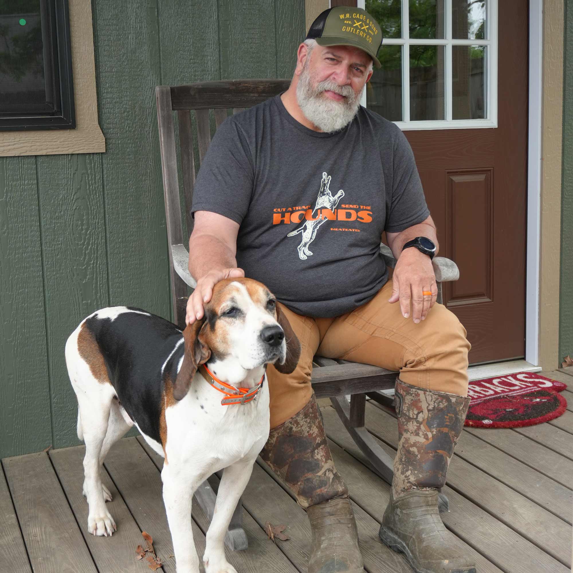 Brent Reaves in rocking chair with hound dog on porch.