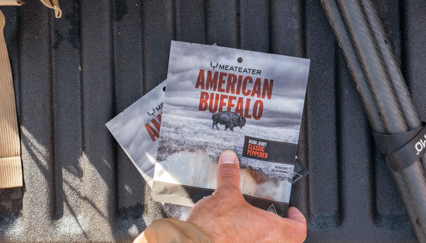 Hand holding a 'Meateater American Buffalo' product package against a textured surface.