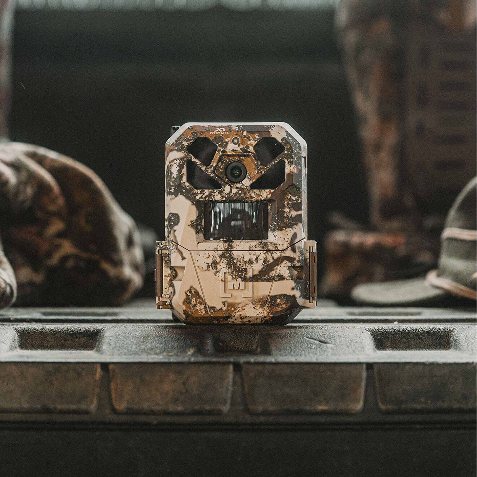 Camouflage-patterned hunting camera on a table with a blurred background