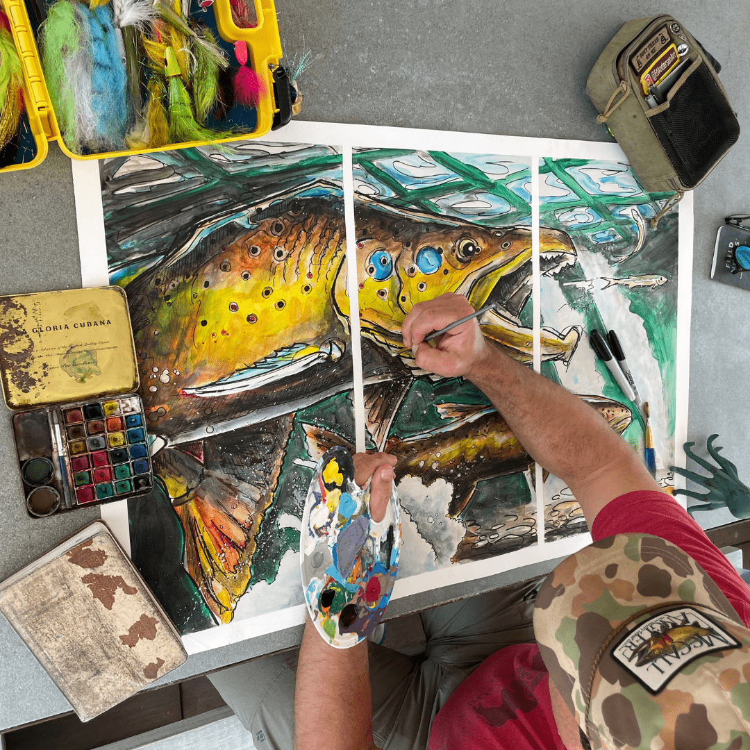 Artist painting vibrant brown trout artwork across three panels with brush and palette.