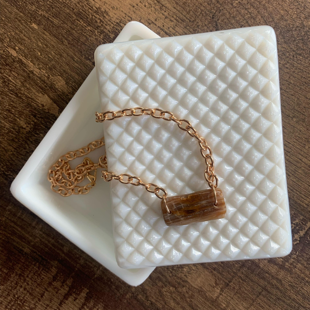 Gold chain necklace with rectangular brown banded stone pendant.