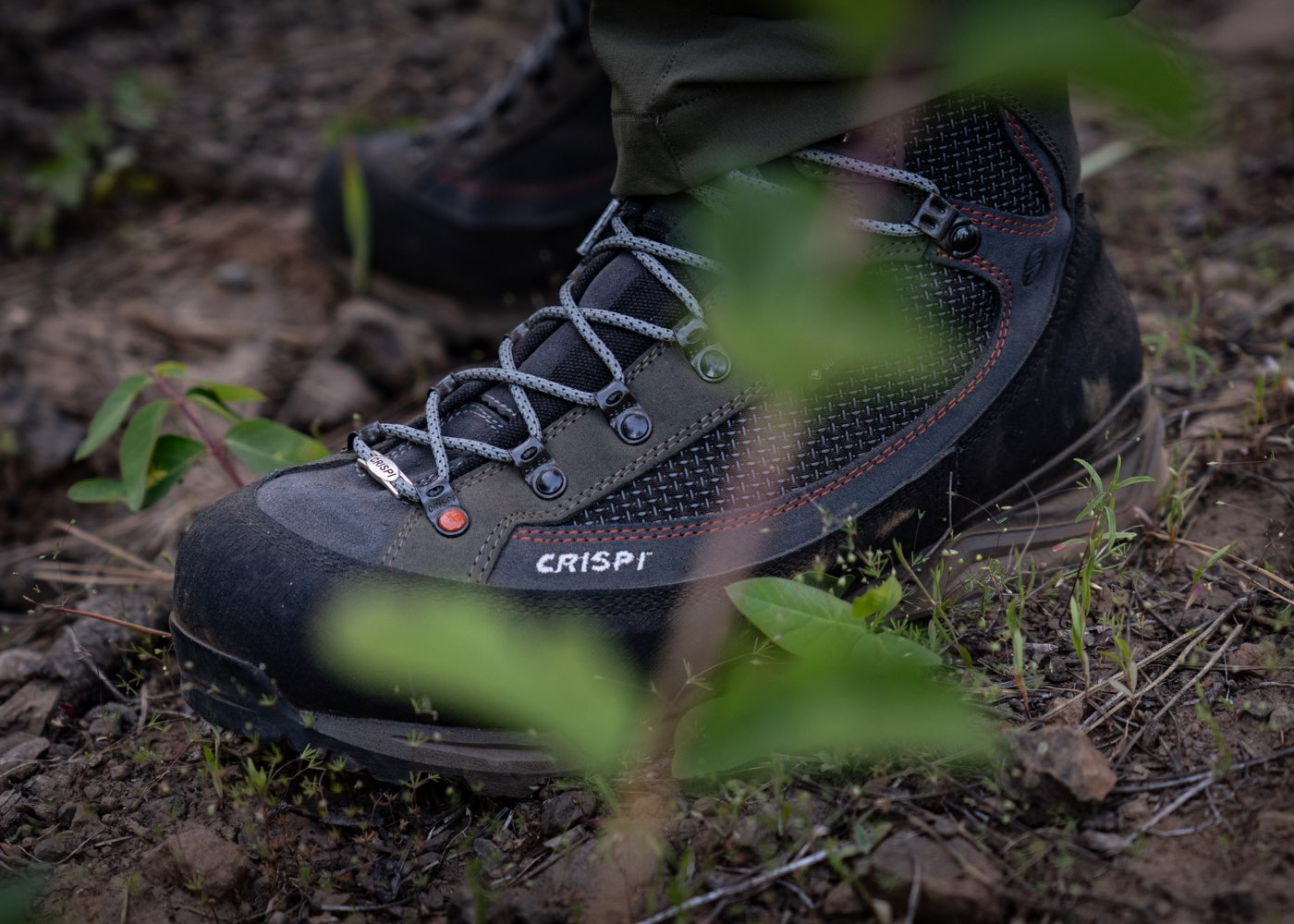 Close up shot of Crispi hunting boots with vegetation and dirt in the background