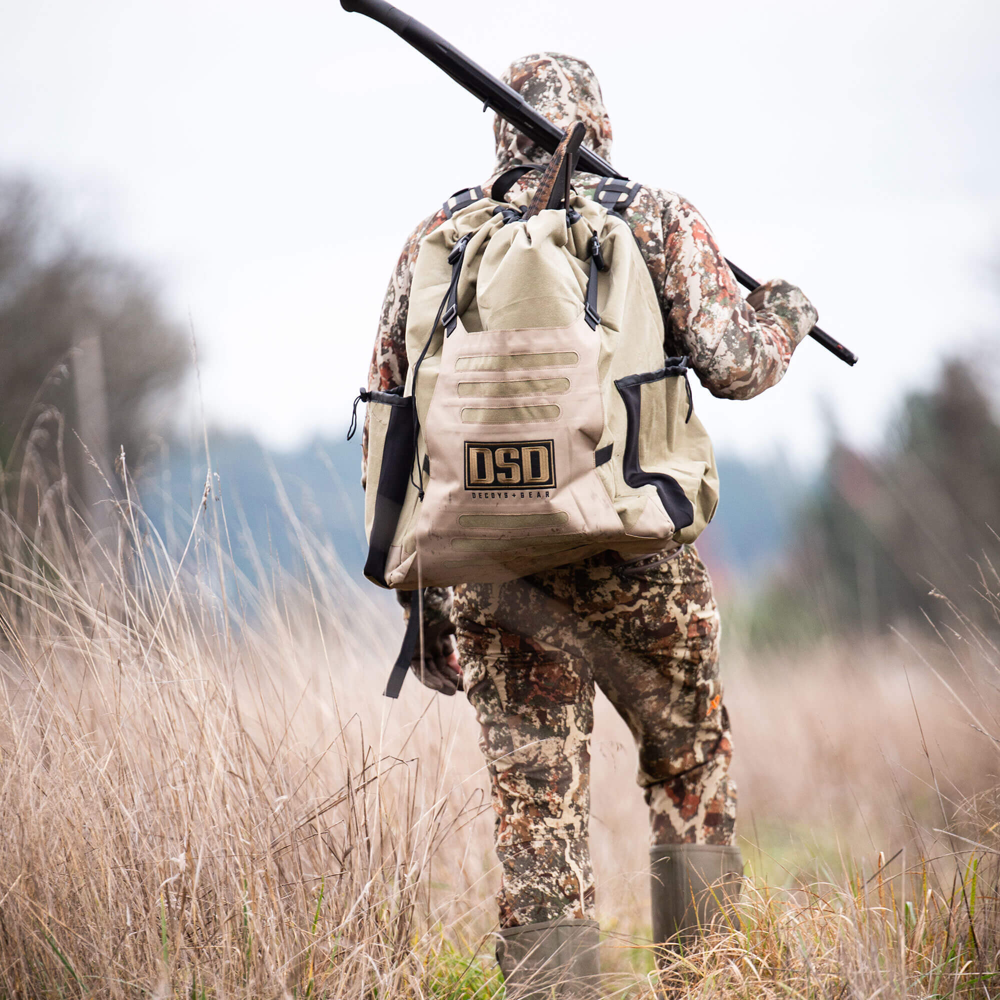 Tan DSD Decoys + Gear backpack on a hunter with a shotgun.