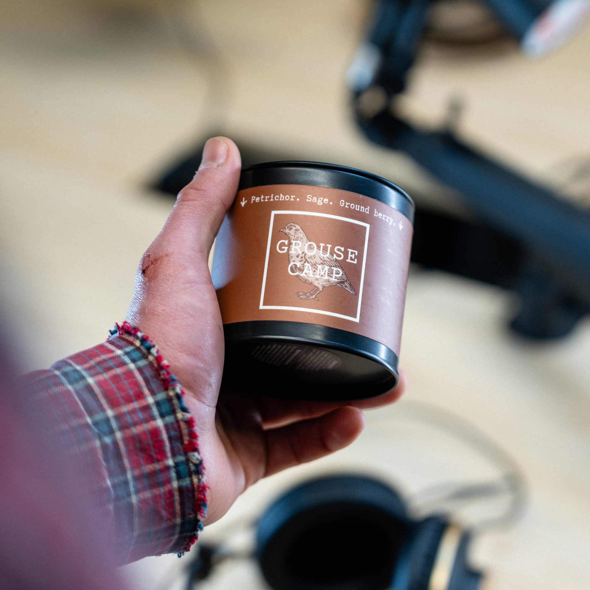 Person holding Grouse Camp scented candle. 