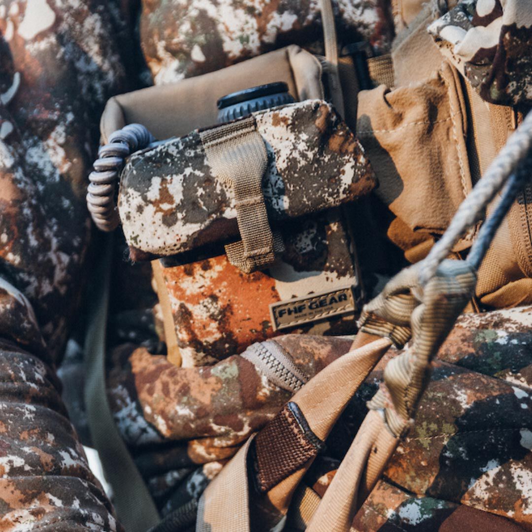 Brown speckled camo FHF GEAR utility pouch with coiled cord, strap, and zipper.