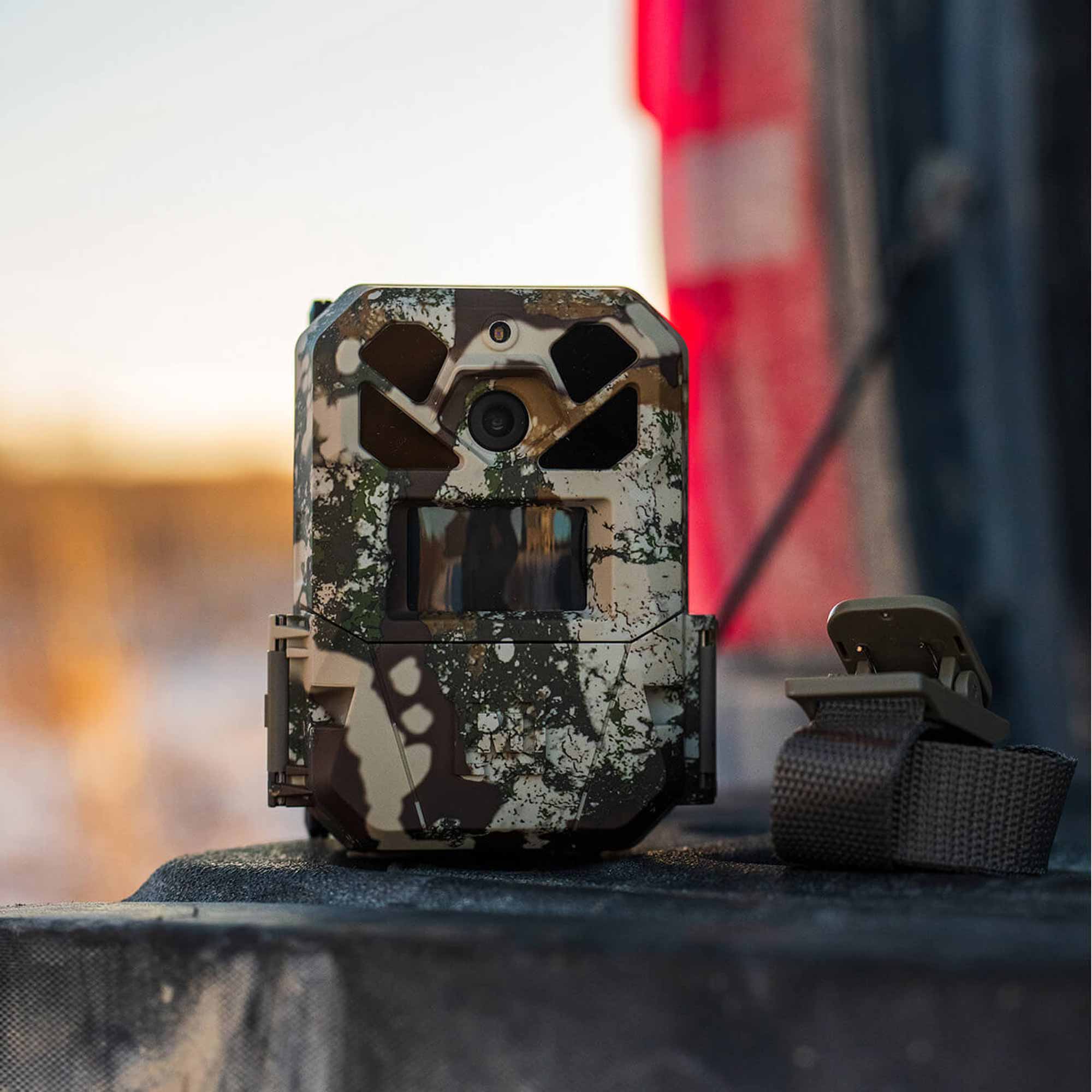 Camouflage-patterned trail camera on a blurred background
