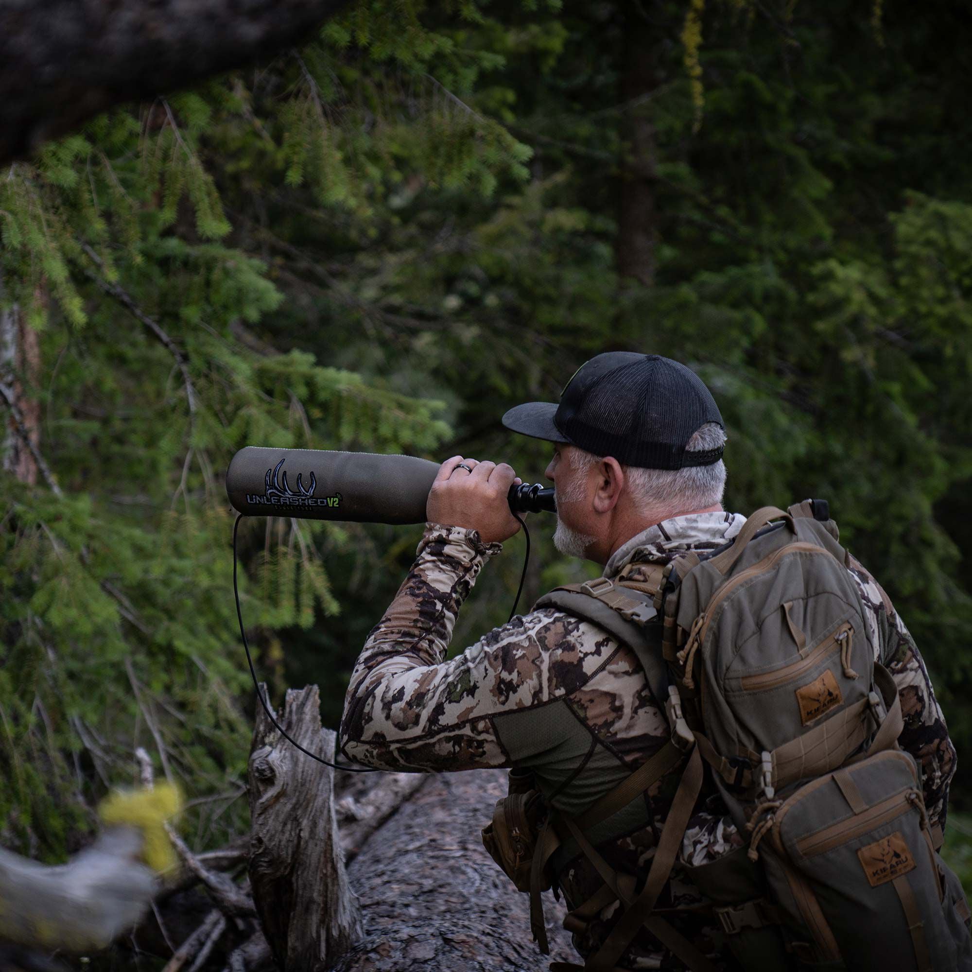 Man using an olive green game call with Unleashed V2 and an antler logo.
